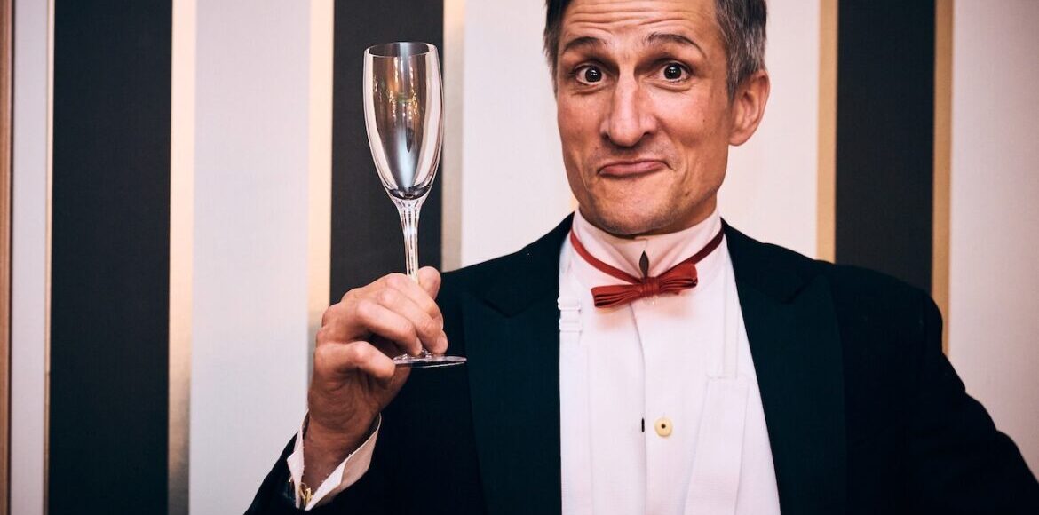 Showkellner hält stilvolles Glas, lächelnd auf Firmenfeier