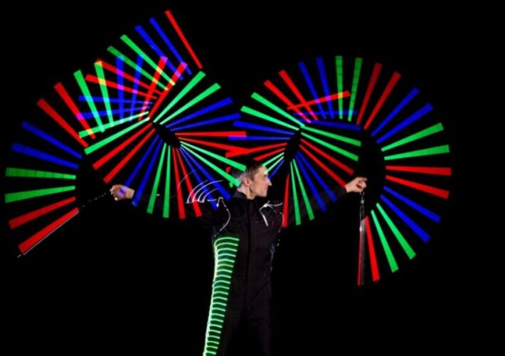 Künstler Markus Just in LED-Anzug erzeugt farbige Muster mit zwei LED-Stäben während seiner Lichtshow