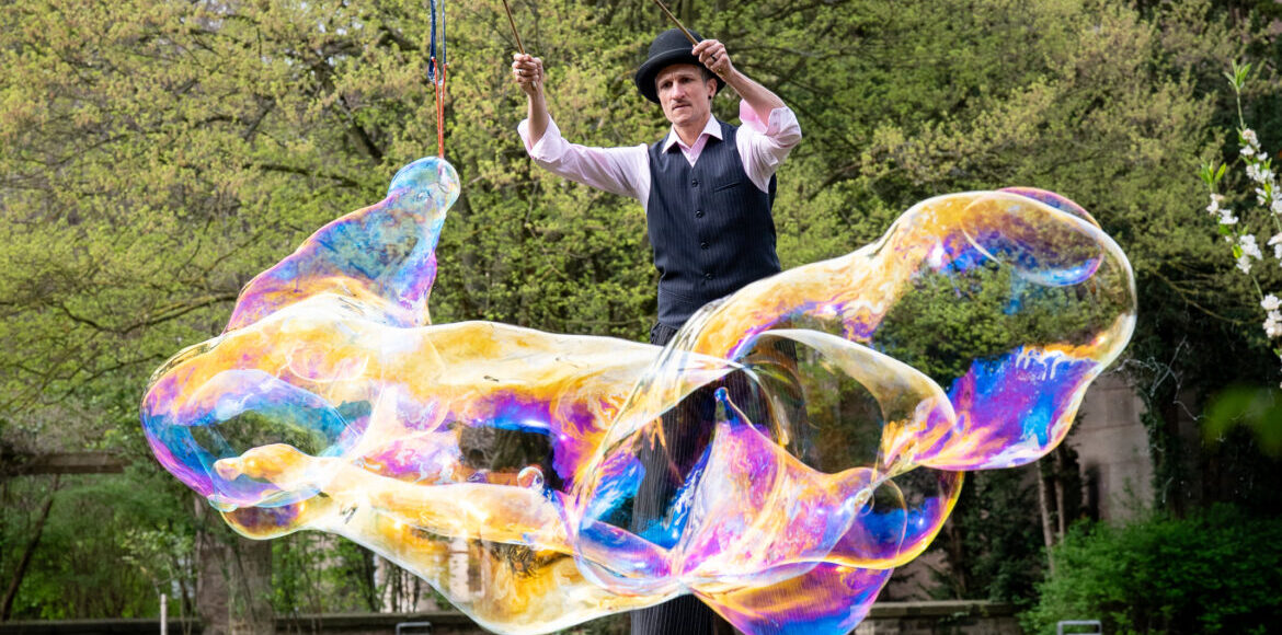 Künstler*in von justnonstop mit Riesenseifenblasen auf Stelzen bei einer Outdoor-Performance